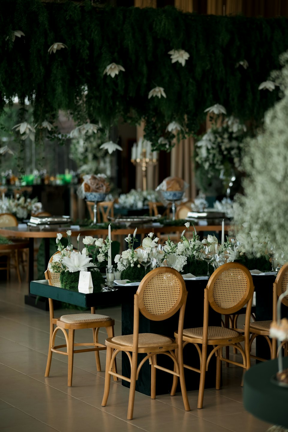 Lange Esstische, geschmückt mit Blumenarrangements und Kerzen.