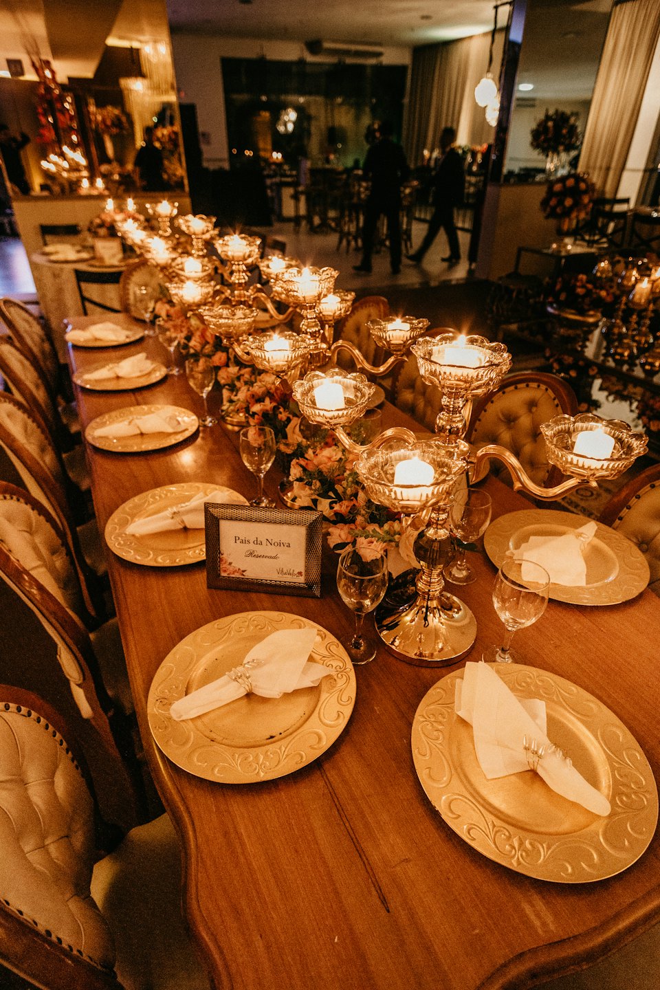 Eleganter Esstisch mit goldenen Tischsets und beleuchteten Kerzenleuchtern.